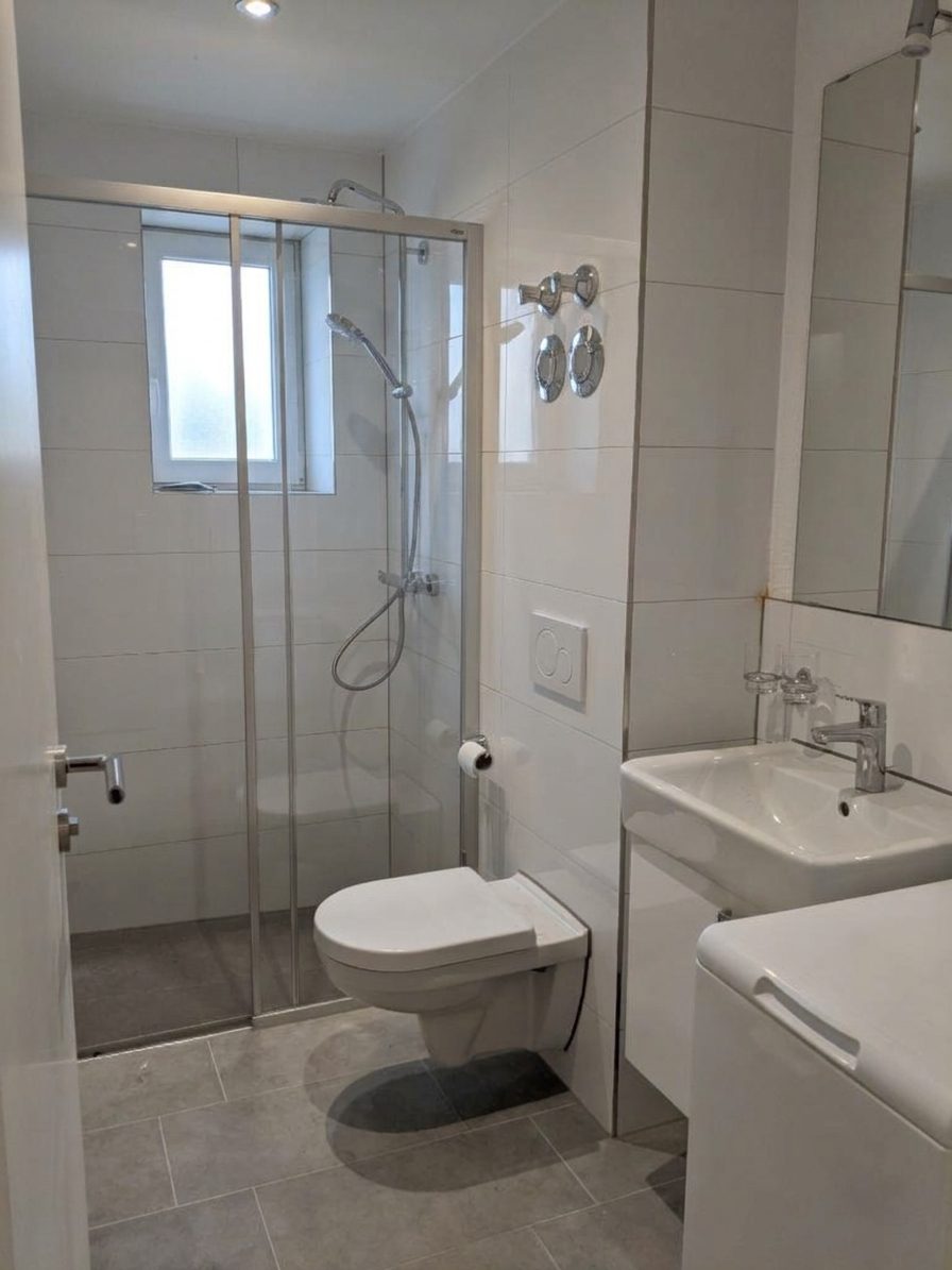 Modernisiertes Duschbad mit Fenster, Glasdusche und wandhängendem WC