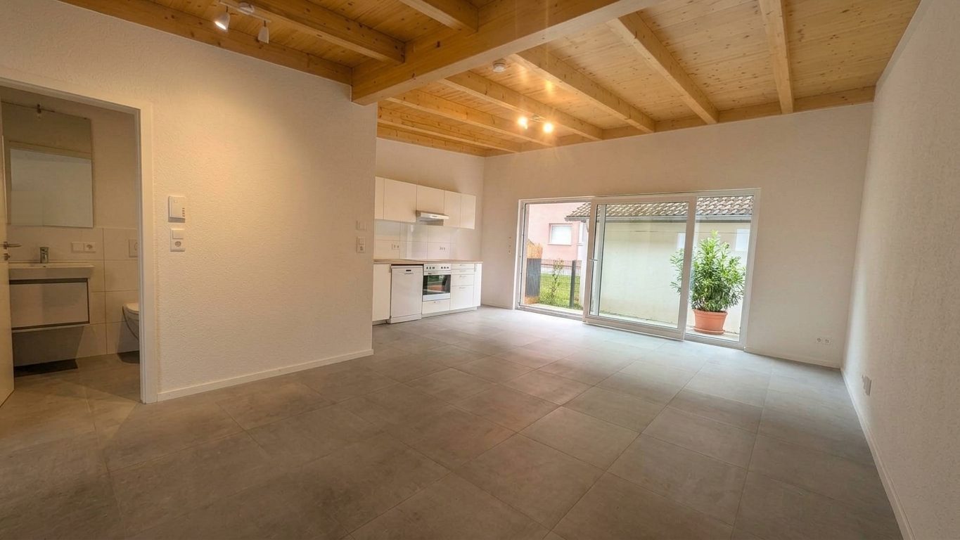 Helles Studio mit Holzbalkendecke, offener Küche und großer Glasschiebetür zur Terrasse